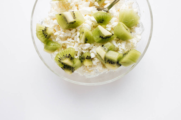 delicioso requesón con trozos de kiwi en un tazón sobre fondo blanco, desayuno saludable
  - Foto, imagen