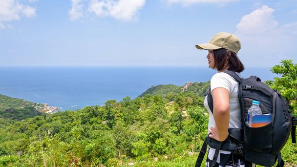 バックパック女性観光客は、スラタニ、タイ、16:9 のワイド画面ではタオ島でキャップ立っている美しい自然風景青い海と空高い風光明媚な視点から見てを着用します。 - 写真・画像