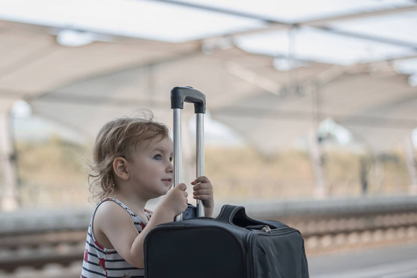 little sweet girl with a big suitcase on a deserted railway platform - Photo, Image