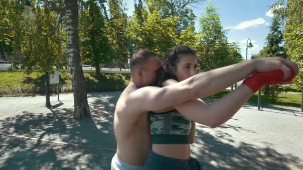 Retrato de un joven sosteniendo a una mujer por detrás, posando un puñetazo de boxeo, cámara lenta
 - Metraje, vídeo