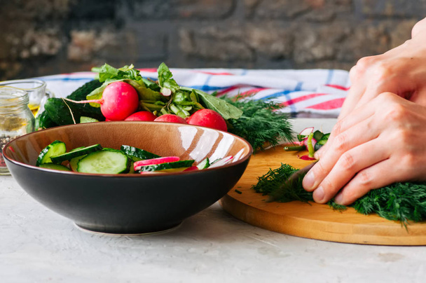 Gezonde salade van verse groenten in maken. Vrouw handen snijden Dille op een houten bord. Stap voor stap concept koken. - Foto, afbeelding