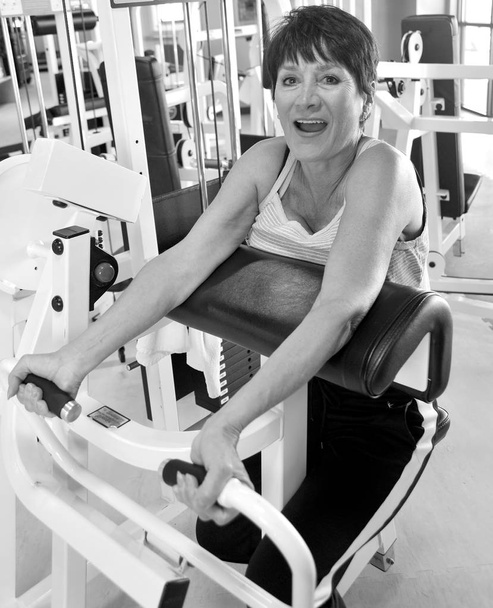 Ältere Seniorinnen trainieren an Gewichtsmaschinen in einem Fitnessstudio. - Foto, Bild