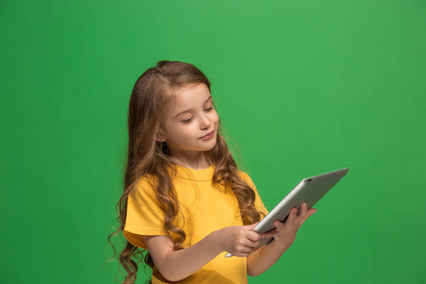 Little funny girl with tablet on green background - Fotó, kép