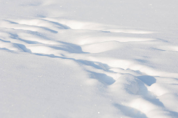 Tekstuuri, tausta, kuvio. Jalanjälkiä lumessa. Pakkanen on hyvin kylmä. Valkoinen lumihuopa maassa. Ilmakehän vesihöyry jäätyy jääkiteissä ja putoaa vaaleisiin valkoisiin hiutaleisiin
  - Valokuva, kuva