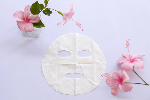 φυσικό φύλλο μάσκα υγειονομική περίθαλψη για δέρμα προσώπου από βότανα λουλούδια σε λευκό φόντο - Φωτογραφία, εικόνα