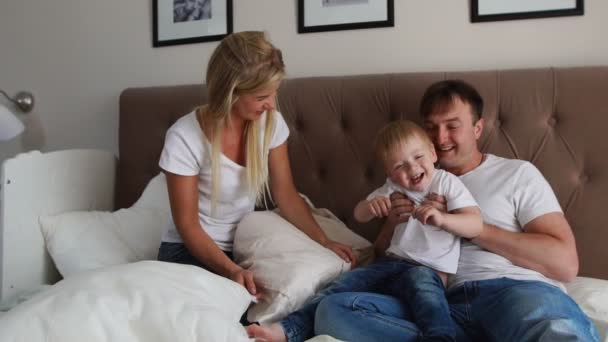 Pais amorosos brincam com seu filho na cama rindo e sorrindo no quarto
 - Filmagem, Vídeo