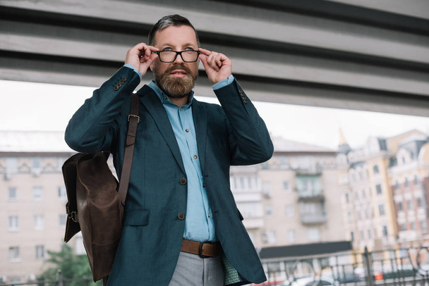 beard stylish businessman in glasses with leather bag in city - Foto, afbeelding