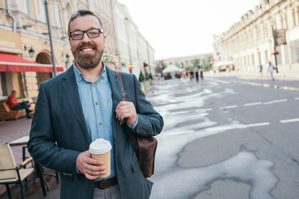 stylish man with leather bag and coffee to go walking in city - Fotoğraf, Görsel