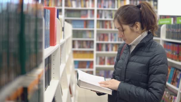 bruneta žena v knihkupectví recenze knihy - Záběry, video