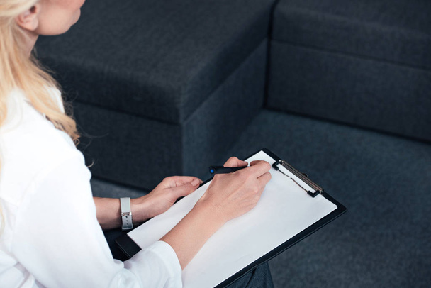 cropped image of female counselor writing in empty clipboard during therapy session in office  - Photo, Image