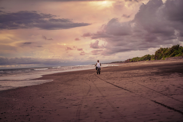 back view of man riding motorcycle on ocean beach  - Фото, зображення