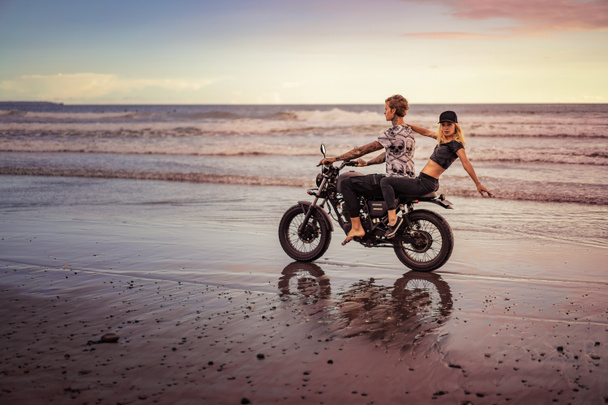 pareja joven montar en motocicleta en la playa del océano
  - Foto, imagen
