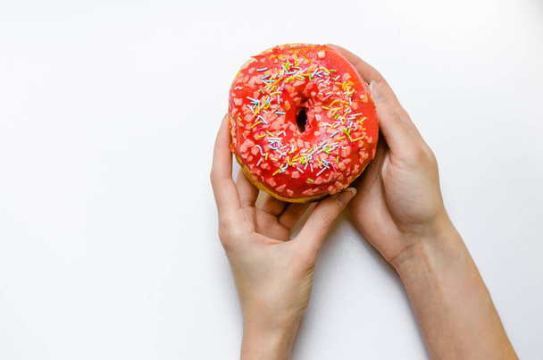 Female hand holding pink donut with sprinkles extra calories fat fast food excess weight unhealthy on yellow background - Foto, Imagem