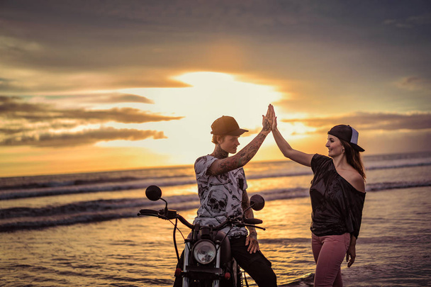 chłopak i dziewczyna dając piątkę w pobliżu motocykla na ocean plaża  - Zdjęcie, obraz