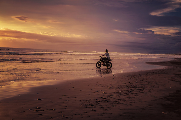 hombre montando moto en el océano durante el amanecer
 - Foto, imagen