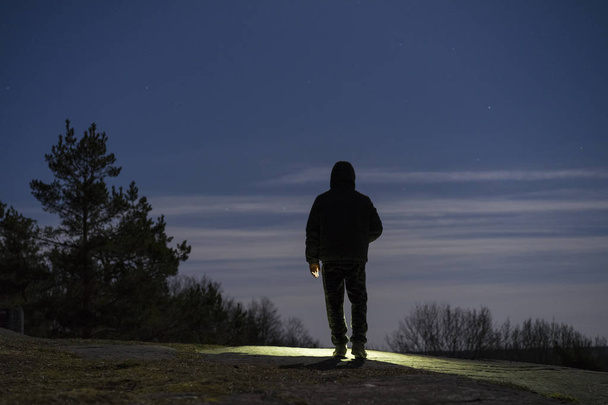 Mann steht nachts mit Taschenlampe im Wald - Foto, Bild