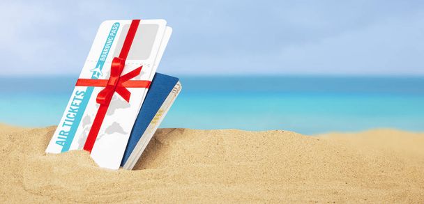Letenky jako dárek s červenou stužkou a luk. Lístky služby Passport a vzduch v písku na pláži u moře - Fotografie, Obrázek