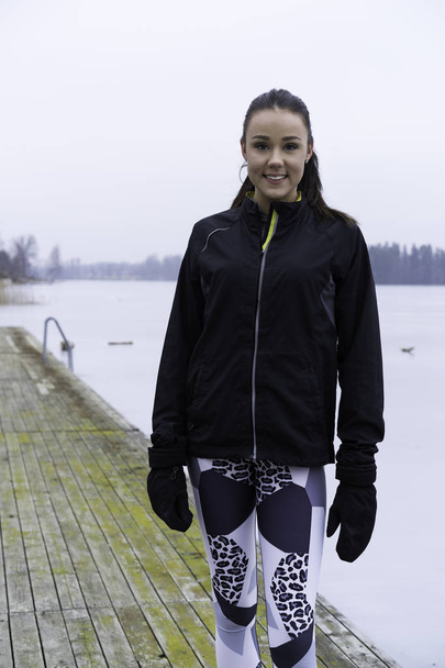 Nádherné fitness dospívající dívka stojící na dřevěný most venku v zimní krajině - Fotografie, Obrázek