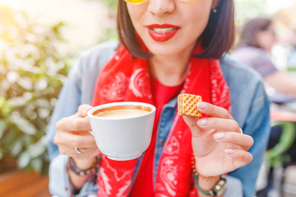 Genç hipster kadın bir kafe açık havada oturma ve kahve içme sarı güneş gözlüğü - Fotoğraf, Görsel