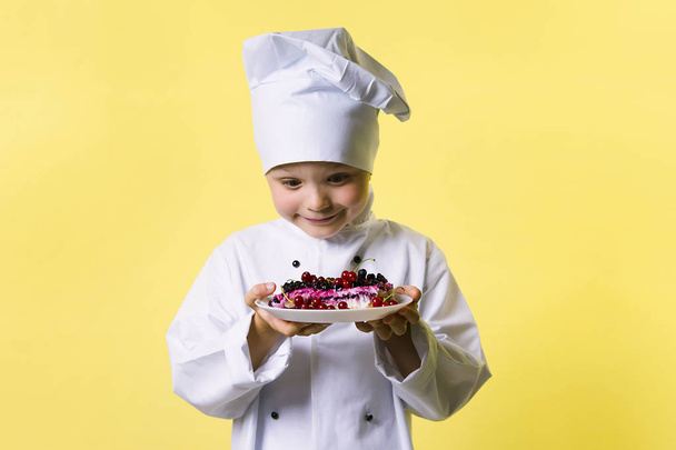 funny boy chef cooked pie with a wig and currant on a plate - Foto, Bild
