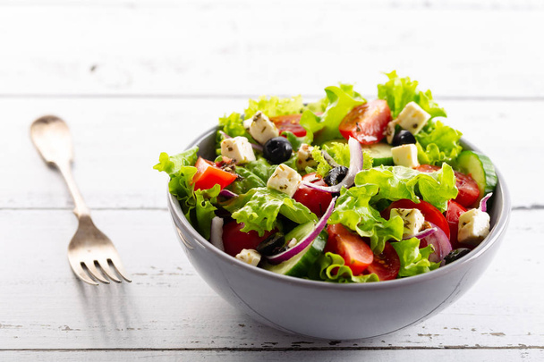 Fresh greek salad served in bowl with fork. - Fotó, kép