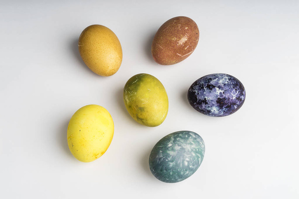 Hermosos huevos de Pascua de color natural sobre fondo blanco. Alimento orgánico crudo con color de solo ingredientes naturales
.  - Foto, Imagen