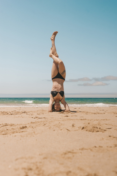 fiatal nő gyakorló headstand homokos strand, a nyári nap - Fotó, kép