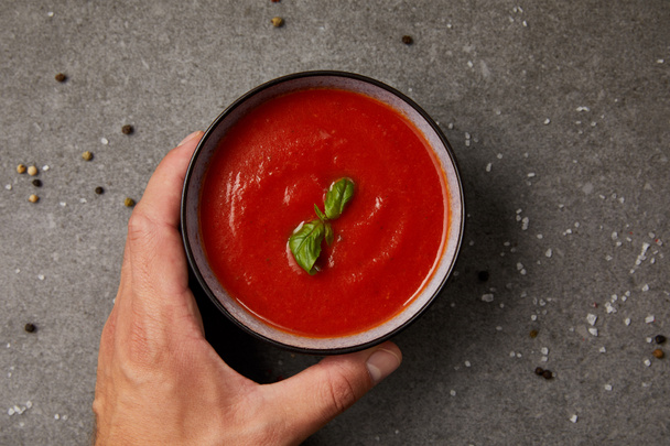 cropped image of man taking plate with tomato soup on grey table - Foto, Bild