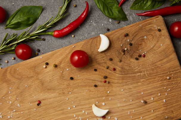 top view of chili peppers, tomatoes and cutting board on grey table - Foto, Imagen