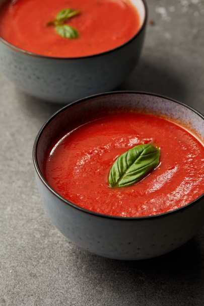 tasty red tomato soup with basil in plates on grey table - Photo, Image