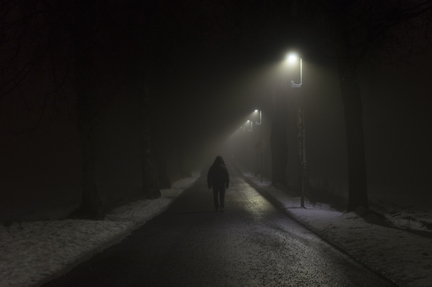 silueta de un hombre caminando en el camino oscuro de la ciudad con faroles de la calle - Foto, Imagen