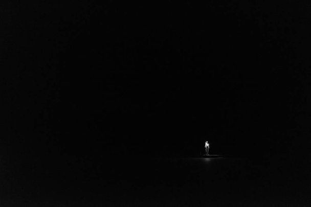 Mies seisoo ulkona yöllä metsässä loistaa taskulamppu ylhäällä pimeällä taivaalla ja puissa
. - Valokuva, kuva