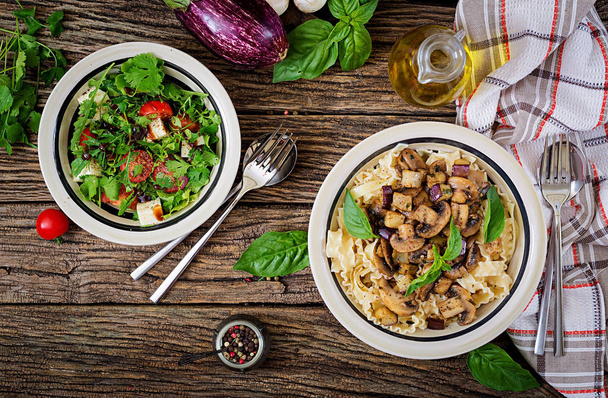 Vegetarische pasta met champignons en aubergines, aubergines en salade. Italiaans eten. Veganistische maaltijd. Bovenaanzicht. Plat leggen. - Foto, afbeelding