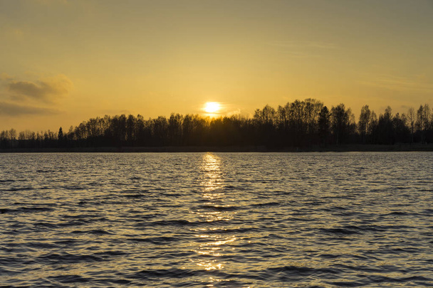 Mooie natuur en landschap foto van kleurrijke zonsondergang in lente avond in Zweden Scandinavië Europa. Mooi buiten beeld met lake, bomen en lucht. Rustig, vreedzaam achtergrondafbeelding. - Foto, afbeelding