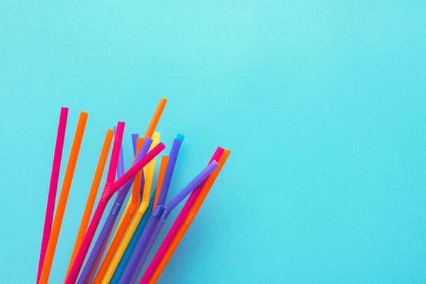 Summer season background, colorful drinking straws on blue backdrop with copy space - 写真・画像