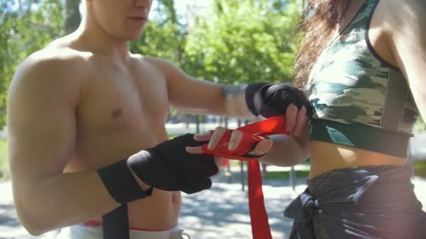 Férfi boxer csavarja a kezek fiatal nő segít neki, a Park - slowmotion edzés - Felvétel, videó
