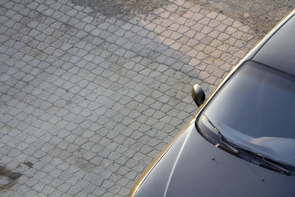 Close-up boven bekijken detail van nieuwe glanzende zwarte luxe dure auto met donkere ramen geparkeerd op schone lege stoep op zonnige dag. Persoonlijke vervoer en parkeren problemen concept. - Foto, afbeelding