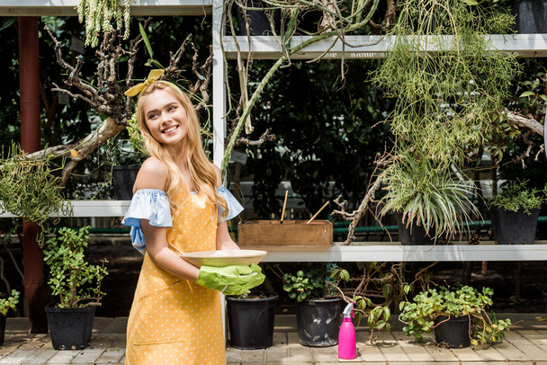 beautiful happy young woman looking away while working in greenhouse - Фото, зображення