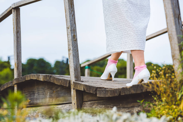 plan recadré de femme en robe blanche marchant sur passerelle en bois
  - Photo, image
