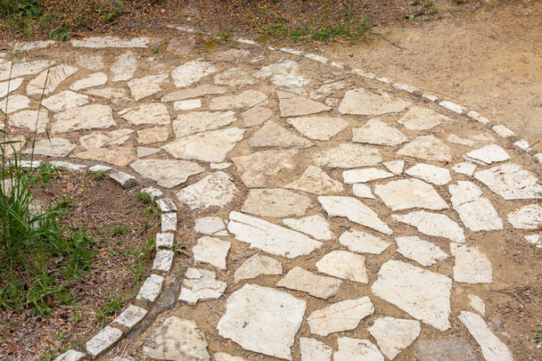 Blokk a kövek, alkotó kör alakú utat. Mintás tégla bélés a járdán. Nem kívánt gyom és növekszik a talajban. Nem hagyományos háztáji és kerttervezés - Fotó, kép