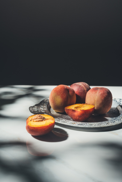 food composition with ripe peaches on metal tray on marble tabletop with black background - Foto, immagini