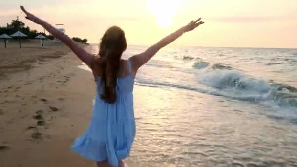 Ağır çekim: sığ suda günbatımında çalışan kız. Beyaz elbiseli bir kız denize yakın kenarında sular çalışıyor. Deniz ve plaj ile mutluyum. Özgürlük karşılaşmış. - Video, Çekim
