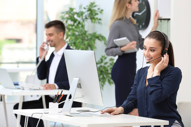 Female receptionist with headset at desk in office - Foto, Bild