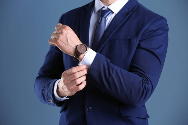 Businessman with wristwatch on color background. Time concept - Valokuva, kuva
