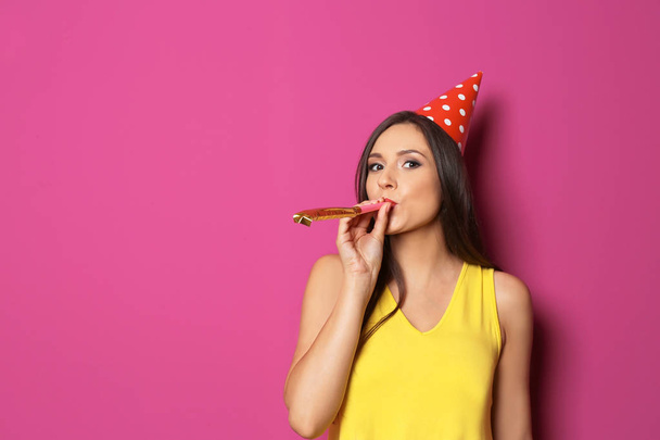Young woman with party blower on color background. Birthday celebration - Фото, зображення