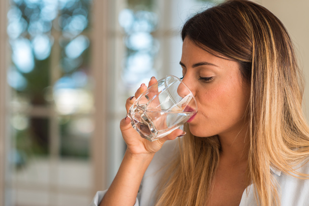 Красива молода жінка п'є склянку води вдома. Концепція стилю
. - Фото, зображення