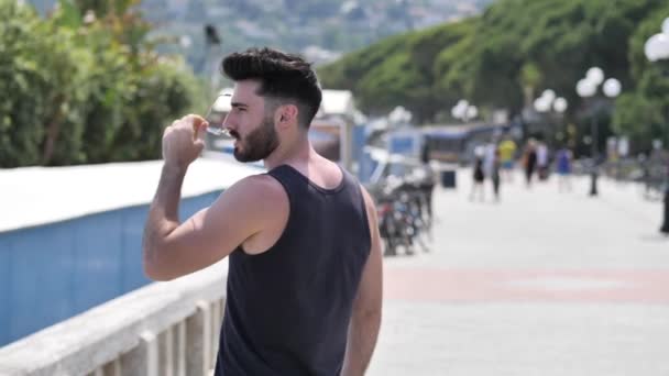 Attractive athletic young man on seaside promenade - Metraje, vídeo