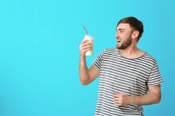 Young man with cup of delicious milk shake on color background - Foto, immagini