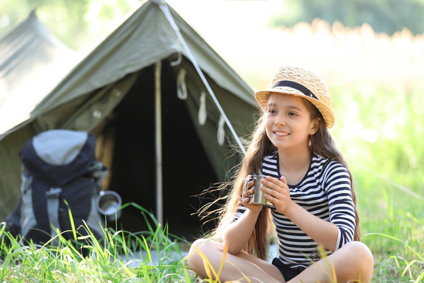 Little girl with mug near tent outdoors. Summer camp - Fotoğraf, Görsel
