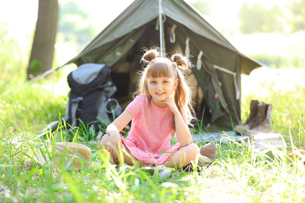 Little girl near tent outdoors. Summer camp - Фото, изображение